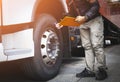 Auto Mechanic is Checking the Truck`s Safety Maintenance Checklist. Lorry Driver. Inspection Truck Safety of Semi Truck Wheels