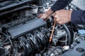 Auto mechanic checking vehicleÃ¢â¬â¢s engine oil level to changing car engine oil