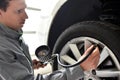 Auto mechanic checks the air pressure of a tire in the garage Royalty Free Stock Photo