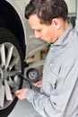 Auto mechanic checks the air pressure of a tire in the garage Royalty Free Stock Photo