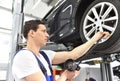 Auto mechanic checks the air pressure of a tire in the garage Royalty Free Stock Photo