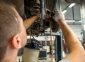 An auto mechanic connects a brake fluid replacement device to a brake drum fitting