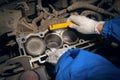 An auto mechanic with a flashlight inspects the engine block and pistons. Repair services