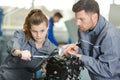 Auto mechanic guiding female trainee in garage