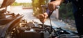 Auto mechanic hands using wrench to repair a car engine.