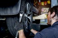Auto mechanic handsome worker man checking wheel tires at garage, car service technician checking and repairing customer car at Royalty Free Stock Photo