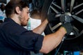 Auto mechanic handsome worker man checking wheel tires at garage, car service technician checking and repairing customer car at Royalty Free Stock Photo