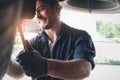 Auto mechanic handsome worker man checking wheel tires at garage, car service technician repairing customer car vehicle, Royalty Free Stock Photo