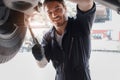 Auto mechanic handsome worker man checking wheel tires at garage, car service technician repairing customer car vehicle, Royalty Free Stock Photo