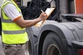 Auto mechanic holding clipboard checking maintenance program of semi truck. truck inspection safety driving. Royalty Free Stock Photo