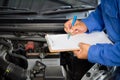 Auto mechanic holding clipboard checklist the car at mechanic shop, Mockup blank clipboard, Technician doing the checklist for