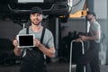 auto mechanic holding digital tablet with blank screen while colleague working Royalty Free Stock Photo