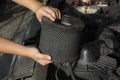 Auto mechanic  holding a dirty, air filter over a car engine for cleaning Royalty Free Stock Photo