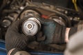 Auto mechanic inspects the timing belt tensioner roller of a passenger car Royalty Free Stock Photo
