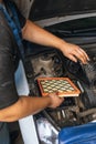 An auto mechanic installs a new engine air filter in a passenger car