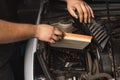 Auto mechanic installs new engine air filter in a passenger car, scheduled maintenance