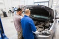 Auto mechanic and man or car owner at workshop Royalty Free Stock Photo