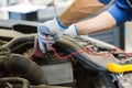 Auto mechanic man with multimeter testing battery Royalty Free Stock Photo