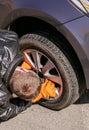 Auto mechanic man in orange gloves removes front tire Royalty Free Stock Photo