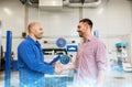 Auto mechanic and man shaking hands at car shop Royalty Free Stock Photo