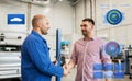 Auto mechanic and man shaking hands at car shop Royalty Free Stock Photo