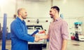 Auto mechanic and man shaking hands at car shop Royalty Free Stock Photo