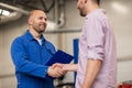 Auto mechanic and man shaking hands at car shop Royalty Free Stock Photo