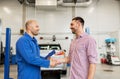 Auto mechanic and man shaking hands at car shop Royalty Free Stock Photo