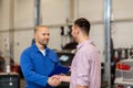 Auto mechanic and man shaking hands at car shop Royalty Free Stock Photo