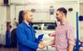 Auto mechanic and man shaking hands at car shop Royalty Free Stock Photo