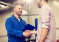 Auto mechanic and man shaking hands at car shop Royalty Free Stock Photo