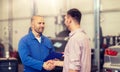 Auto mechanic and man shaking hands at car shop Royalty Free Stock Photo