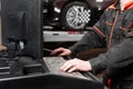 Auto mechanic performs diagnostics and configuration on the computer . Wheel alignment equipment on a car wheel in a