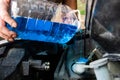 Auto mechanic pours windshield washer fluid into the car. Royalty Free Stock Photo