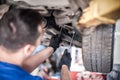 Auto mechanic repairer checking condition under car on vehicle lift