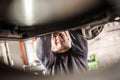 Auto mechanic repairer checking condition under car on vehicle lift