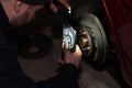 An auto mechanic repairs a brake disc on the wheel of his car in the garage. A man replaces worn-out brakes on a car Royalty Free Stock Photo