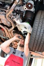 Auto mechanic repairs vehicle in a workshop