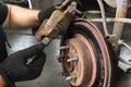 An auto mechanic is replacing brake pads, tightens a screw into a brake caliper