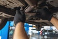 An auto mechanic unscrews the oil drain plug in the cars crankcase with a key