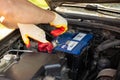 An auto mechanic unscrews a VARTA car battery mount for removal and repair. Battery replacement. Royalty Free Stock Photo