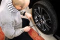 Auto mechanic unscrews wheel bolts with a wrench