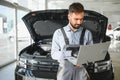 Auto mechanic using computer diagnostic program while repairing car in workshop Royalty Free Stock Photo