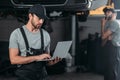 auto mechanic using laptop while colleague working Royalty Free Stock Photo