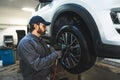 Auto mechanic using pneumatic wrench to replace wheel on white car on a hoist Royalty Free Stock Photo