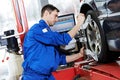 Auto mechanic at wheel alignment work with spanner Royalty Free Stock Photo
