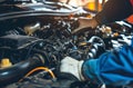 Auto mechanic working on car engine in mechanics garage. Repair service. authentic close-up shot Royalty Free Stock Photo