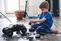 Auto modeling: little boy repairing a model radio-controlled car at home.