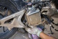 Auto motorcycle radiator Being disassembled by the hands of a motorbike mechanic Hands wearing gloves. So soiled cloth