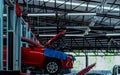 Auto repair shop. Red SUV car is lift in garage for repair and maintenance service. Auto service with lifted vehicle. Car body Royalty Free Stock Photo